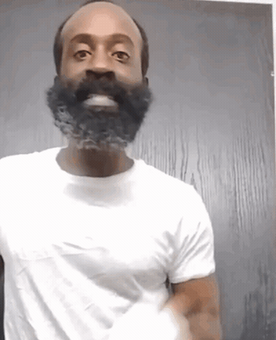 A Man With A Beard Is Wearing A White Shirt And Smiling GIF