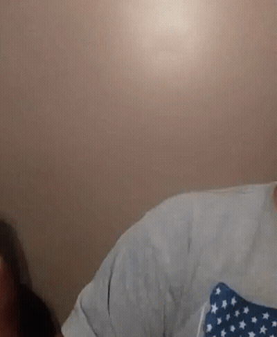 A Man With A Beard Is Wearing A White Shirt With A Blue And White American Flag On It . GIF