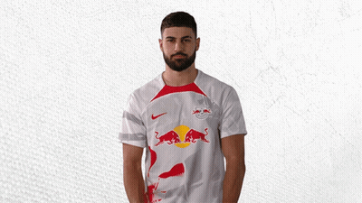 A Man With A Beard Is Wearing A White Shirt With A Red Bull On It GIF