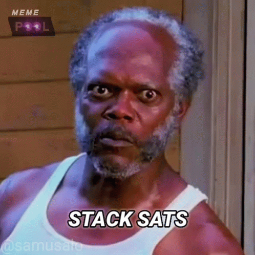 A Man With A Beard Is Wearing A White Tank Top And Saying Stack Sats GIF