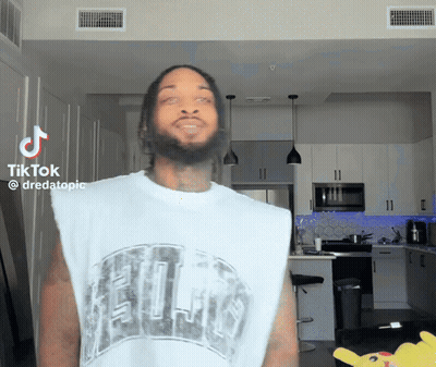 A Man With A Beard Is Wearing A White Tank Top That Says ' Chicago ' On It GIF