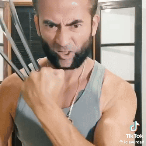 A Man With A Beard Is Wearing A Wolverine Costume And Holding His Claws Out . GIF