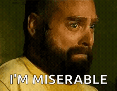 A Man With A Beard Is Wearing A Yellow Shirt And Saying I 'M Miserable . GIF