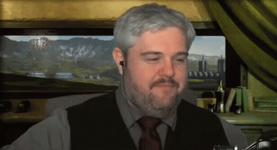A Man With A Beard Is Wearing Ear Buds And A Vest And Tie GIF