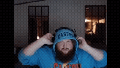 A Man With A Beard Is Wearing Headphones And A Blue Casedy Hoodie . GIF