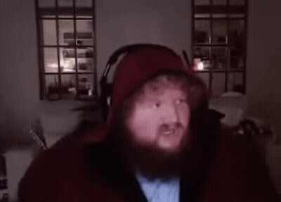 A Man With A Beard Is Wearing Headphones And A Hoodie . GIF