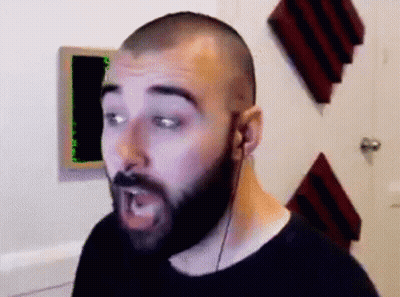 A Man With A Beard Is Wearing Headphones And Making A Face . GIF