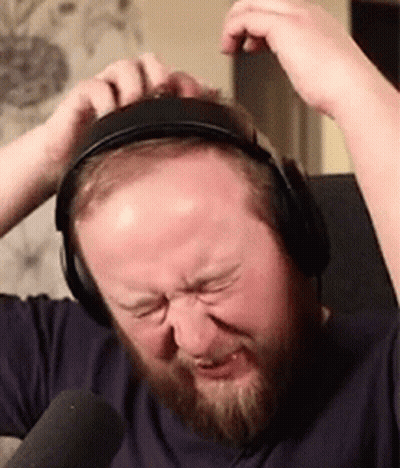 A Man With A Beard Is Wearing Headphones And Making A Face . GIF