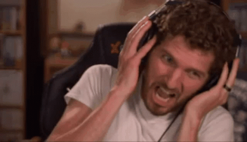 A Man With A Beard Is Wearing Headphones And Making A Funny Face . GIF