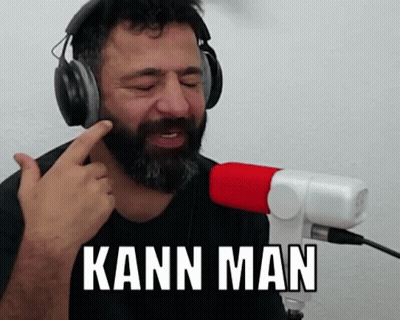A Man With A Beard Is Wearing Headphones And Singing Into A Microphone While Saying Kann Man . GIF