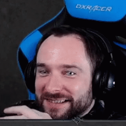 A Man With A Beard Is Wearing Headphones And Sitting In A Blue And Black Chair . GIF