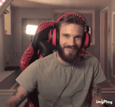 A Man With A Beard Is Wearing Headphones And Smiling While Sitting In An Office Chair GIF