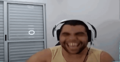 A Man With A Beard Is Wearing Headphones And Smiling While Sitting In Front Of A Window . GIF