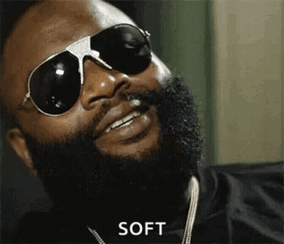 A Man With A Beard Is Wearing Sunglasses And A Necklace . GIF