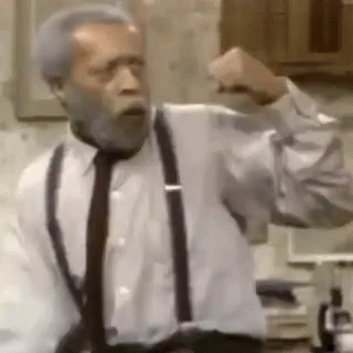 A Man With A Beard Is Wearing Suspenders And A Tie And Is Making A Fist . GIF