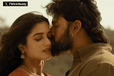 A Man With A Beard Kisses A Woman On The Forehead In Front Of A Sign That Says 7Wickreddy GIF