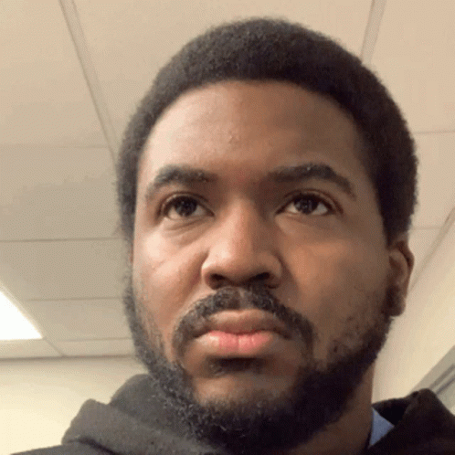 A Man With A Beard Looks At The Camera GIF