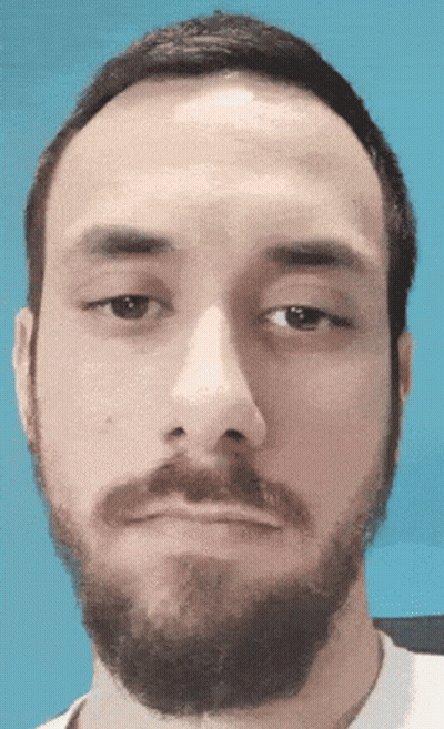 A Man With A Beard Looks At The Camera With A Blue Background GIF