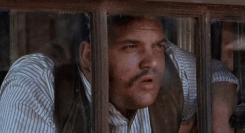 A Man With A Beard Looks Out A Window GIF