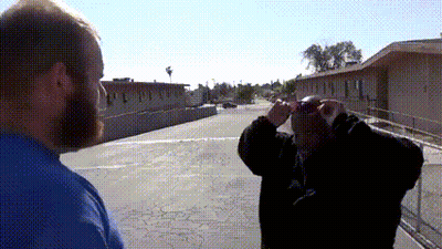 A Man With A Beard Looks Through Binoculars At Another Man GIF