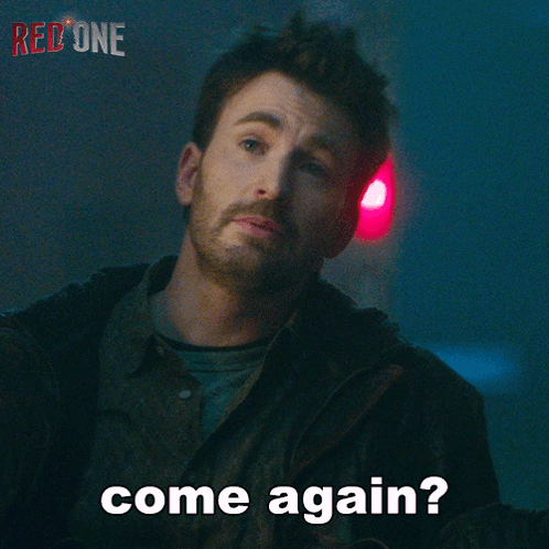 A Man With A Beard Says Come Again In Front Of A Red Light GIF
