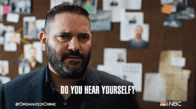 A Man With A Beard Says " Do You Hear Yourself " In Front Of A Wall Of Pictures GIF