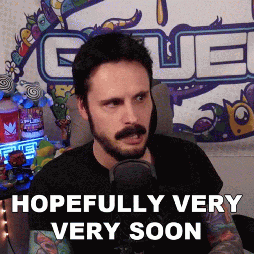 A Man With A Beard Says Hopefully Very Very Soon In Front Of A Fuel Sign GIF