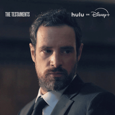 A Man With A Beard Says " Not Yet " In Front Of A Poster For The Testaments GIF