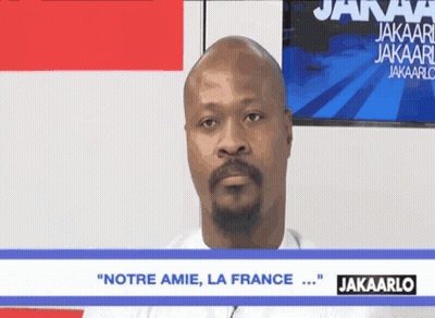 A Man With A Beard Says " Notre Amie La France " On A Screen GIF