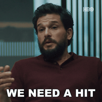 A Man With A Beard Says " We Need A Hit " In White Letters GIF