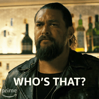 A Man With A Beard Says Who 'S That In Front Of A Bar GIF