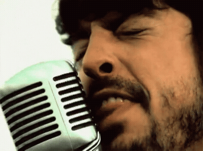 A Man With A Beard Singing Into A Microphone With His Eyes Closed GIF