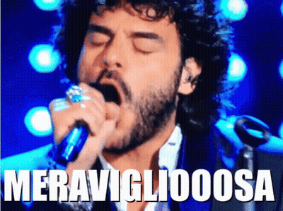 A Man With A Beard Singing Into A Microphone With The Word Meravigliaoosa Written Above Him GIF