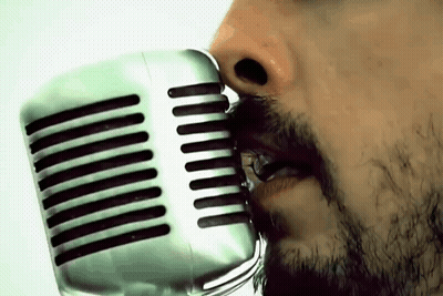 A Man With A Beard Singing Into A Silver Microphone GIF