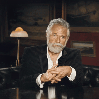 A Man With A Beard Sitting At A Table With His Hands Outstretched GIF