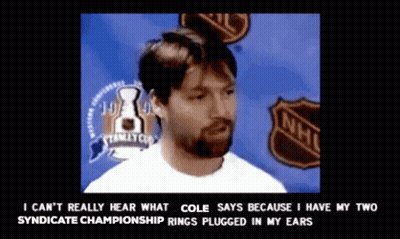 A Man With A Beard Stands In Front Of A Nhl Sign GIF