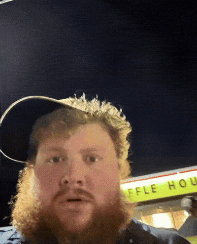A Man With A Beard Stands In Front Of A Waffle House Sign GIF
