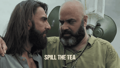 A Man With A Beard Stands Next To Another Man With The Words Spill The Tea On The Bottom GIF