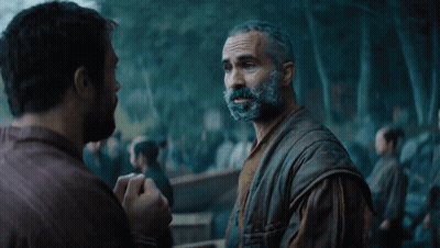 A Man With A Beard Talks To Another Man In Front Of A Crowd GIF