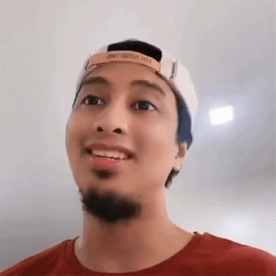 A Man With A Beard Wearing A Baseball Cap And A Red Shirt Is Smiling . GIF