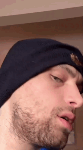 A Man With A Beard Wearing A Beanie Looks At The Camera GIF