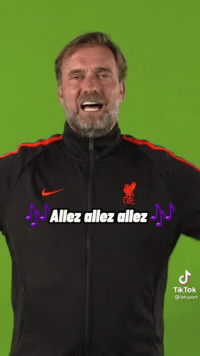 A Man With A Beard Wearing A Black And Orange Nike Jacket Is Smiling . GIF