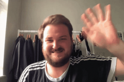 a man with a beard wearing a black and white adidas shirt is waving