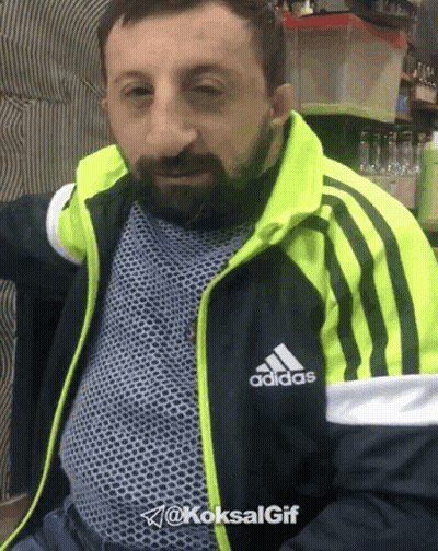 A Man With A Beard Wearing A Black And Yellow Adidas Jacket GIF