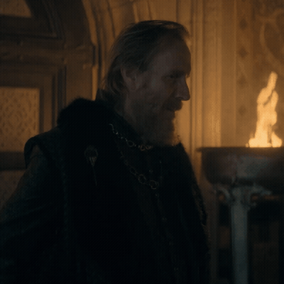 A Man With A Beard Wearing A Black Coat And A Chain Around His Neck GIF