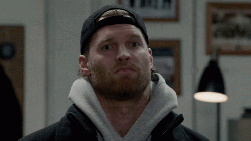 A Man With A Beard Wearing A Black Hat And A Grey Hoodie GIF