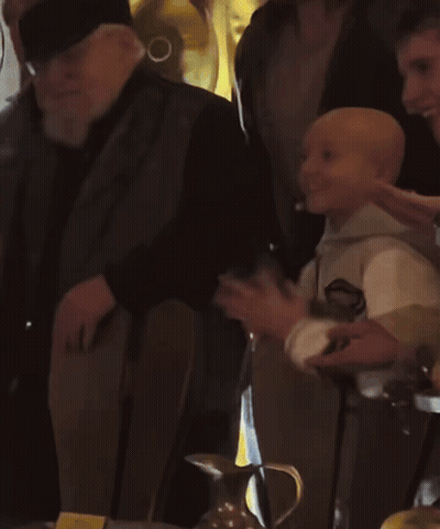 A Man With A Beard Wearing A Black Hat Stands In A Crowd Of People GIF