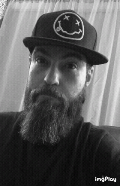 A Man With A Beard Wearing A Black Hat With A Smiley Face On It GIF