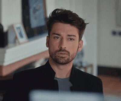 A Man With A Beard Wearing A Black Jacket Looks At The Camera GIF