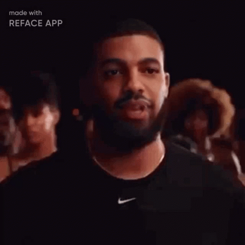A Man With A Beard Wearing A Black Nike Shirt Is Standing In Front Of A Crowd Of People . GIF